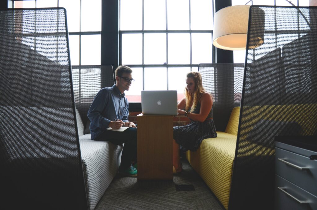 Two people sitting and talking over a computer