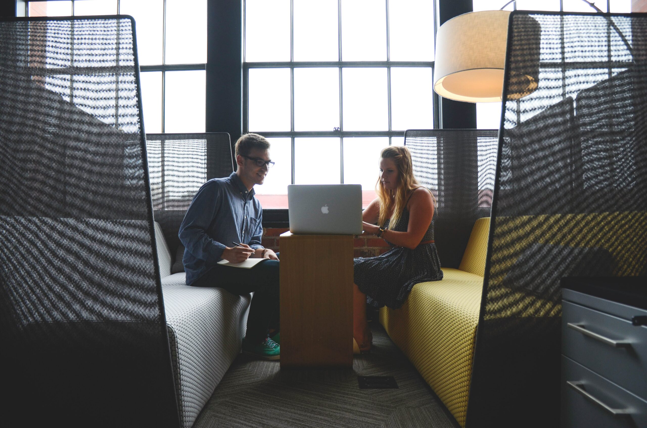Two people sitting and talking over a computer